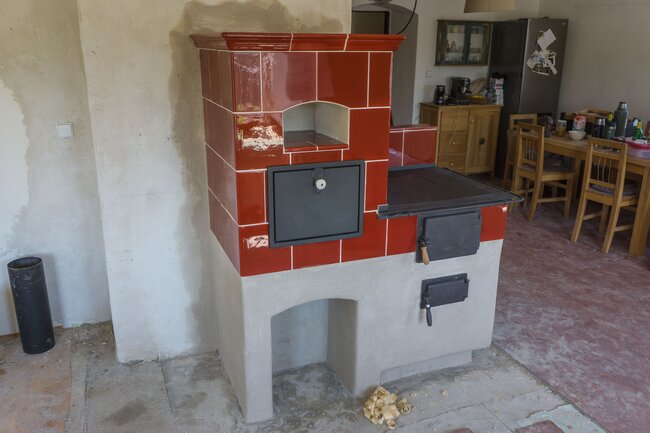 Tradiční kachlový sporák s litinovými dvířky a černým rámem plotny | © Archiv Jana Křivonožky