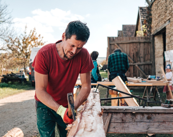 Muž tesající kmen. V rámci akce si zájemci vyzkouší i tesařské řemeslo.