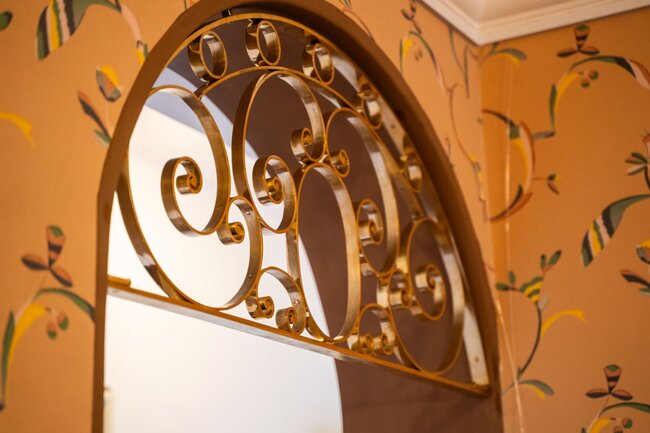 Detail mosazné mříže v oblouku vedoucím k hostinskému pokoji | © Jan Vlček