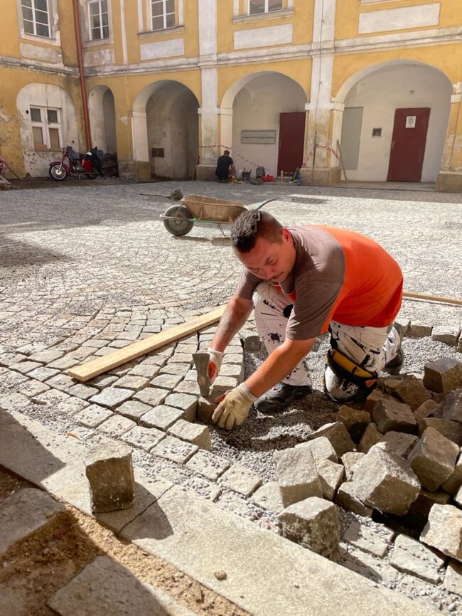 Puklice u Jihlavy, zámek – pokládka kamenné dlažby na železobetonovou desku s hydroizolací na sanovaném nádvoří v roce 2021 | © Lukáš Pečenka