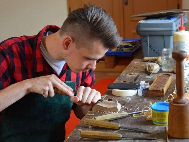 Studenti restaurátorství pracují na obnově nábytku před zraky návštěvníků.