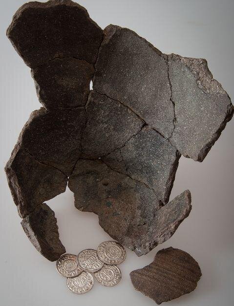 Ukázka denárů Boleslava II. (972–999) z nálezu v Chýšti s fragmentem keramické nádoby, v níž byl poklad uložen.