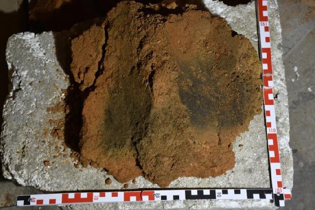Žárem do červena vypálený fragment hliněné omazávky roubených stěn