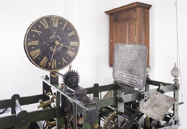 Stroj zahrnuje  historické převodové mechanismy, závaží, bronzové cimbály nebo samostatně stojící ciferník.