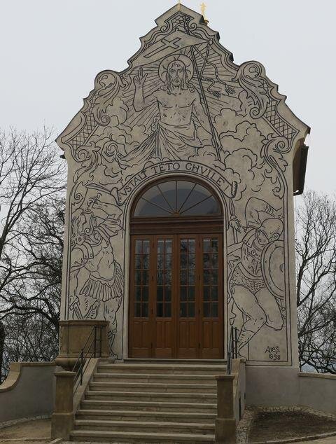 Průčelí kaple zdobí sgrafito podle návrhu Mikoláše Alše.