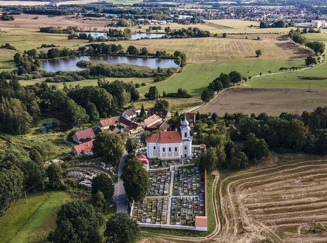 S novou střechou září paštický kostel v kulturní krajině do daleka.