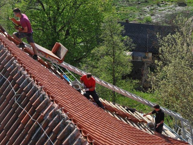 Pokrývači na strmé střeše kostela při práci