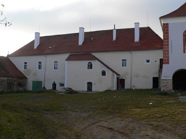 Na západní křídlo zámku navazují hospodářské budovy, z jedné strany již opravené.