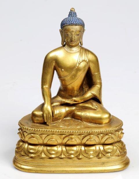 Buddha v mnišském rouchu s gestem dotýkání se země. Usazen je na lotosovém trůně se dvěma řadami lotosových okvětních listů.