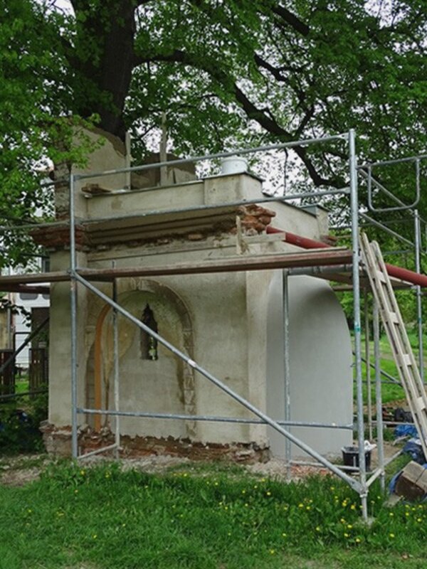 Průčelí kaple z roku 1826 je zdobené pilastry s hlavicemi s vegetativními motivy, v bočních průčelích jsou charakteristické slepé arkády s okénky.