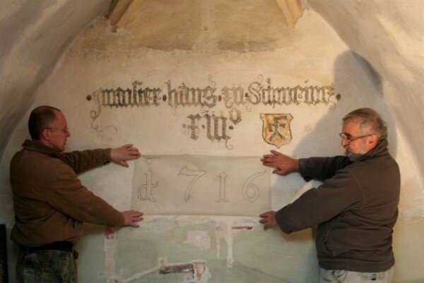 Žumberk – kostel sv. Jana Křtitele - restaurátoři Pavel Hála (vlevo) a Antonín Hamsík u německého pamětního nápisu o vedoucím kameníků a roku dokončení přestavby kostela. 