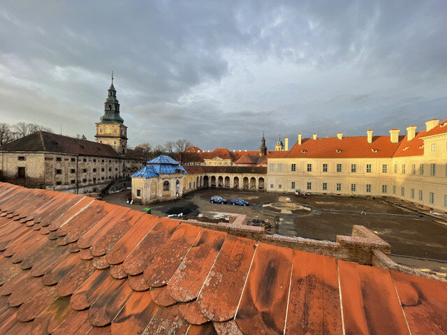 Dvůr s obnovenými fasádami, ambitem a částečný pohled na sýpku