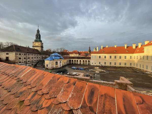 Dvůr s obnovenými fasádami, ambitem a částečný pohled na sýpku