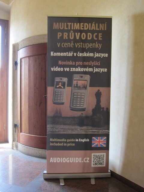 Upoutávka, která zve na výstavu Jakuba Schikanedera pro sluchově hendikepované ve Valdštejsné jízdárně v Praze.